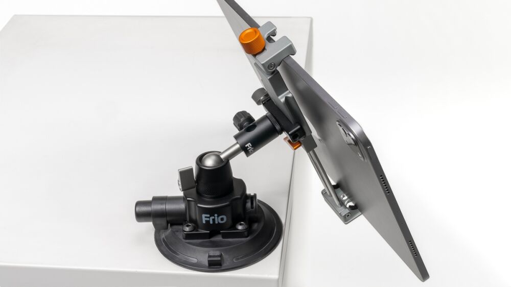 Flat-screen monitor mounted on an adjustable arm clamp attached to a white surface with an orange adjustment knob visible.