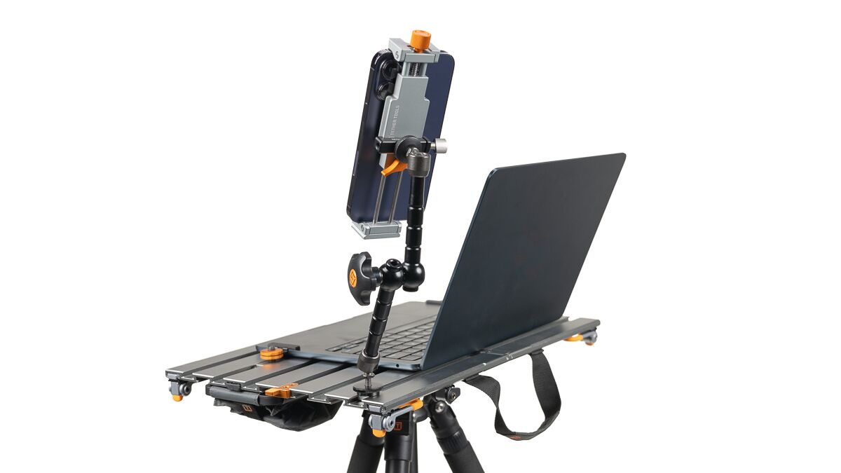 Tripod-mounted workstation rig with a sliding laptop platform and a flexible arm holding a smartphone above it.