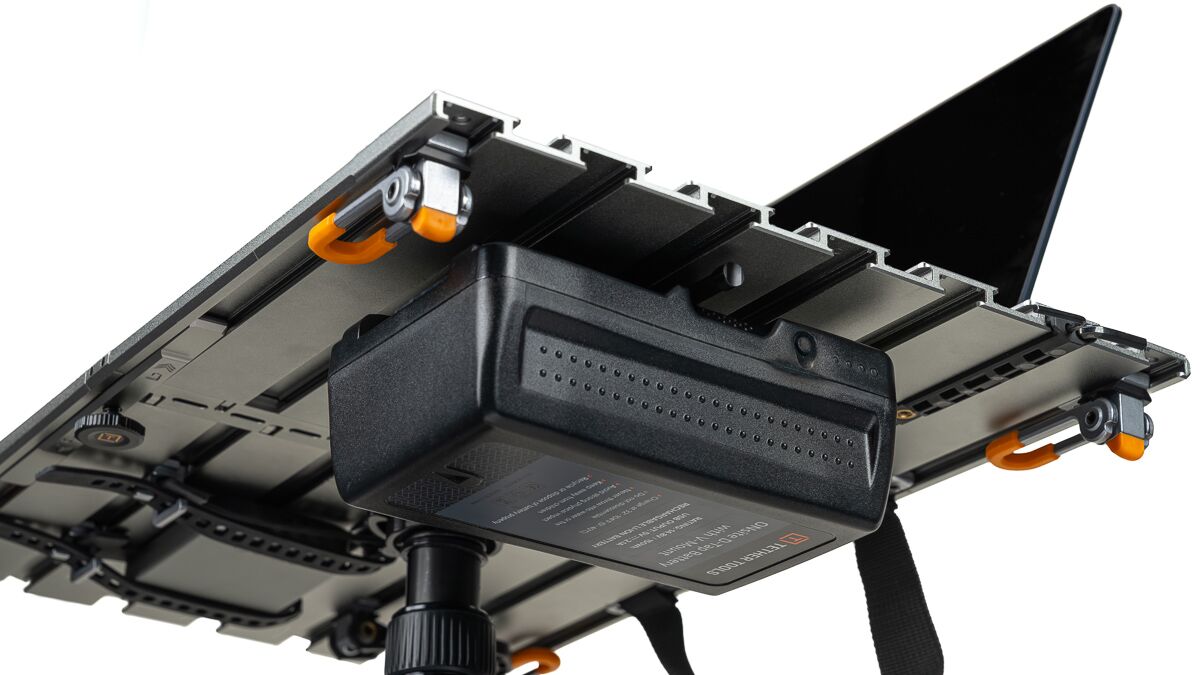 Underside view of a camera rig with a laptop mounted on a metal platform and orange clamps.