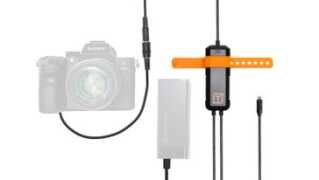 Sony camera connected to a tethering kit with a power/battery adapter and orange-arm clamp for studio use