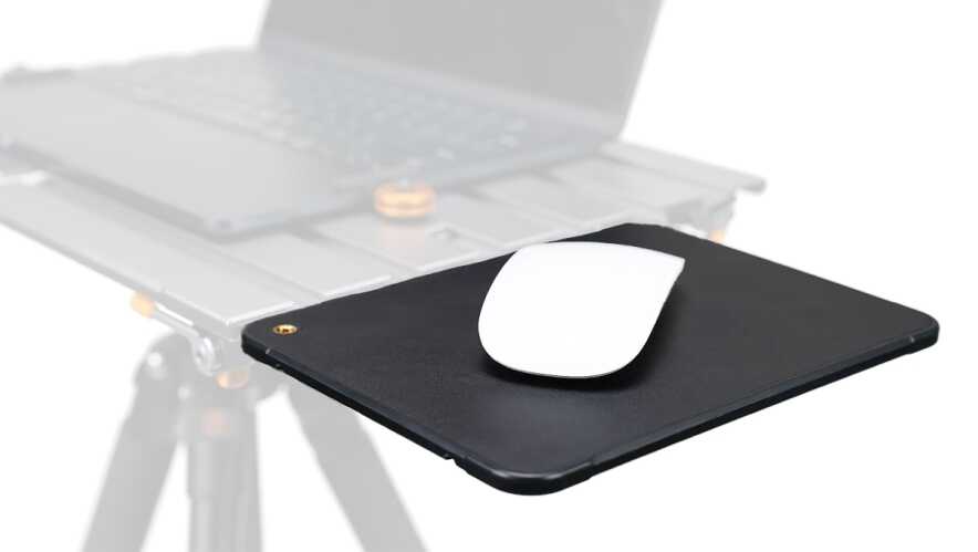 White wireless mouse resting on a black mousepad with a laptop blurred in the background, suggesting a desk setup for computing.