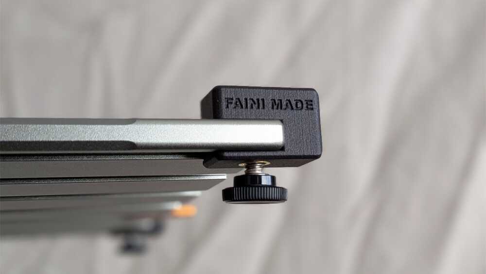 Close-up of a metal camera slider rail with a black end block and a knurled adjustment knob.