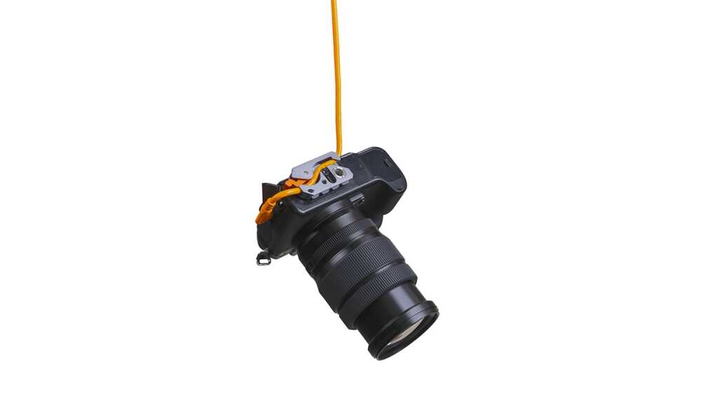 DSLR camera with a long zoom lens hanging from an orange strap against a white background