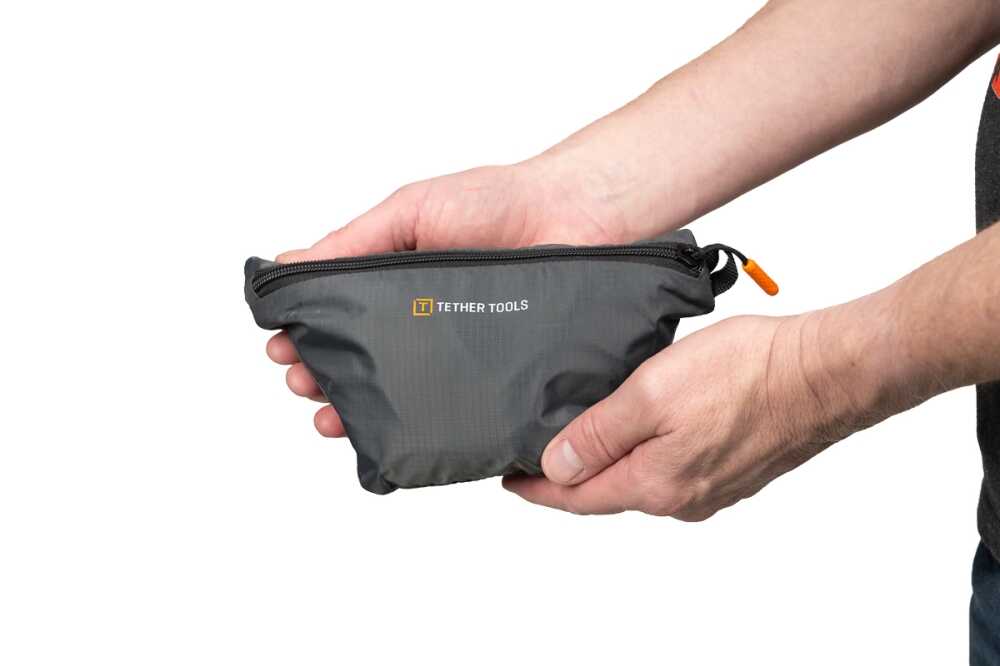 Hands holding a small gray zippered pouch with the Tether Tools logo