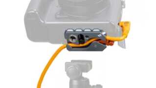 Close-up of a camera with an orange cable secured in a gray quick-release clamp accessory