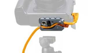 Close-up of a camera with an orange cable secured in a gray quick-release clamp accessory