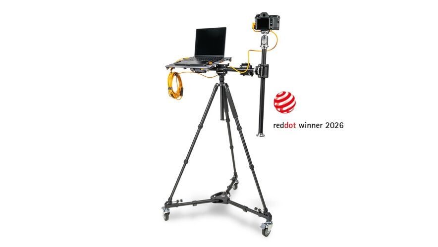 Camera rig with laptop on a wheeled stand and a mounted camera, beside a Red Dot Award 2026 logo