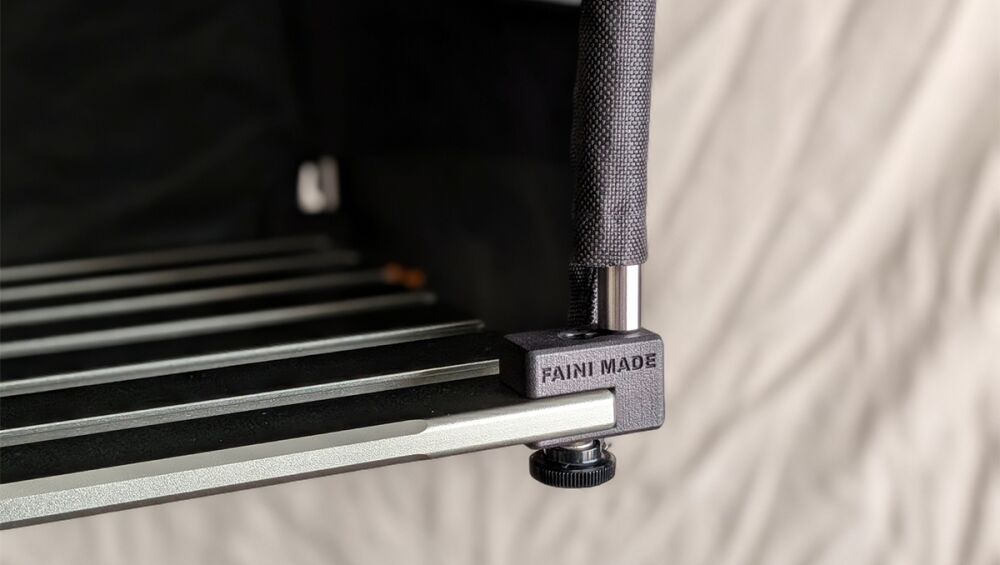 Close-up of a camera rig clamp with a textured grip and knurled adjustment knob, branding reads 'FAINI MADE' on the clamp edge