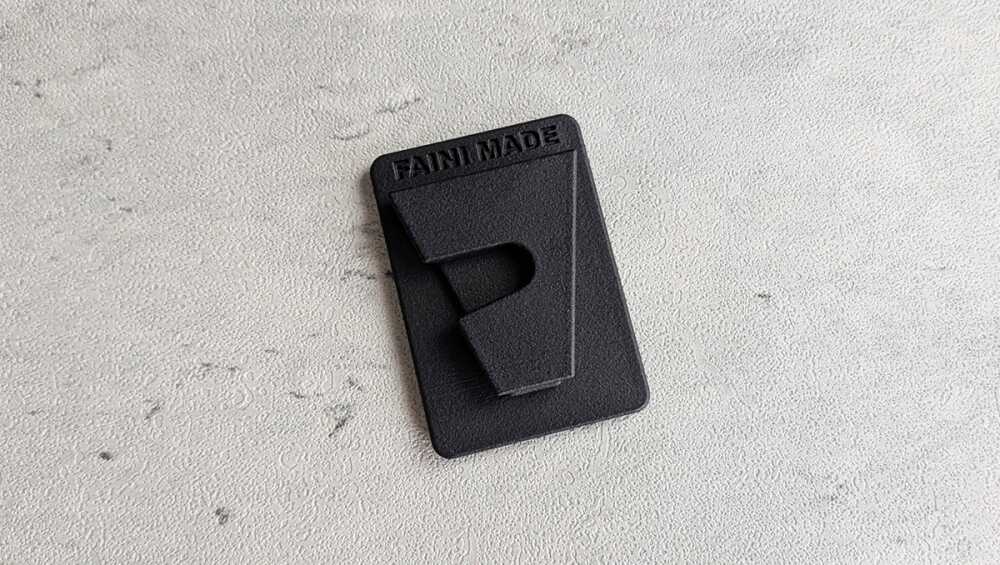 Black rectangular tag with 'FAN MADE' embossed on a gray textured surface.