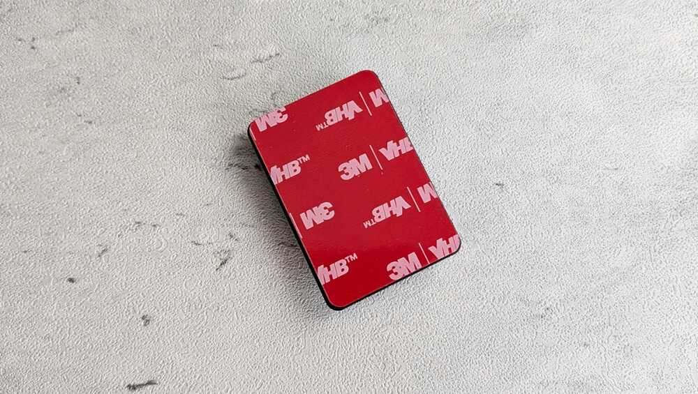 Red square 3M VHB adhesive pad on a light gray background.