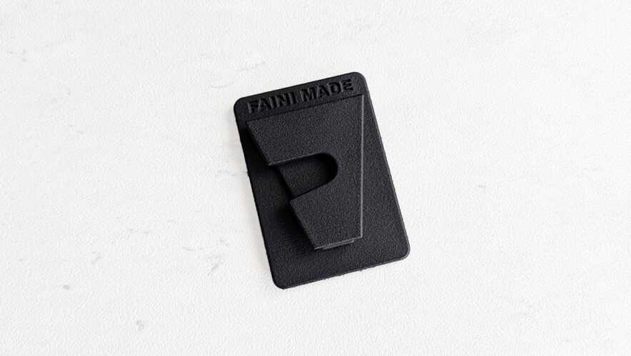 Black rectangular plastic plate with a hinged latch and the words 'FAN MADE' embossed at the top on a pale textured background.