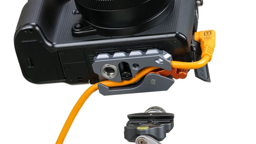 DSLR camera with an orange external power or tether cable connected to a grip accessory.