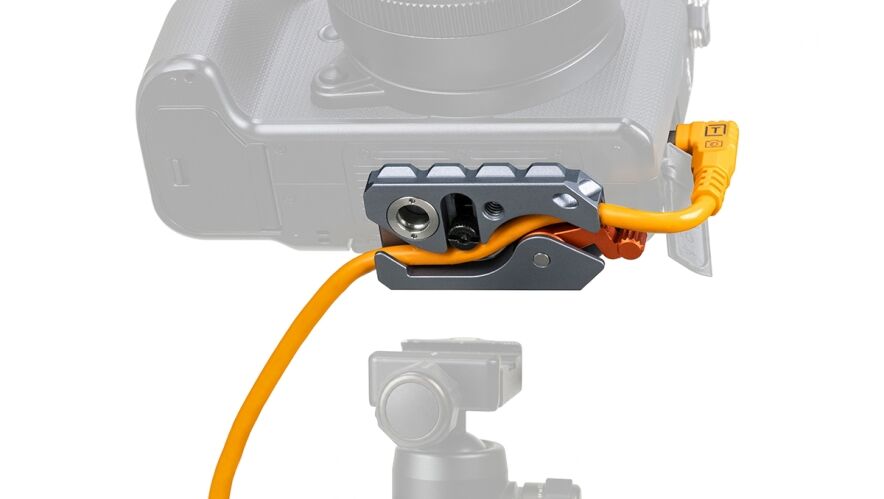 Close-up of a camera with an orange cable secured in a gray quick-release clamp accessory