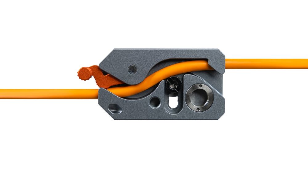 Close-up of a gray wire stripper clamping an orange electrical cable, ready to strip insulation.
