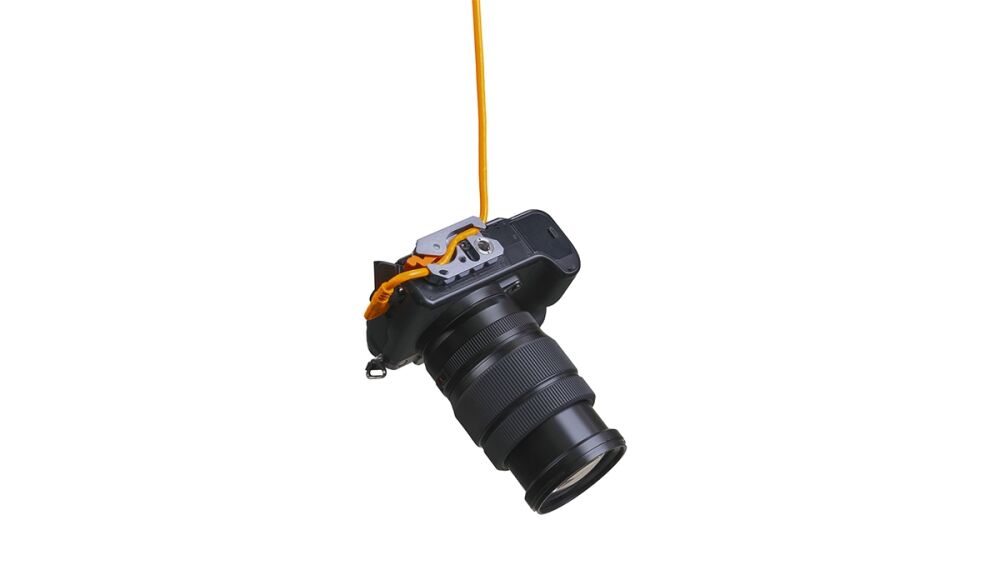 DSLR camera with a long zoom lens hanging from an orange strap against a white background