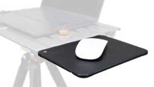 White wireless mouse resting on a black mousepad with a laptop blurred in the background, suggesting a desk setup for computing.