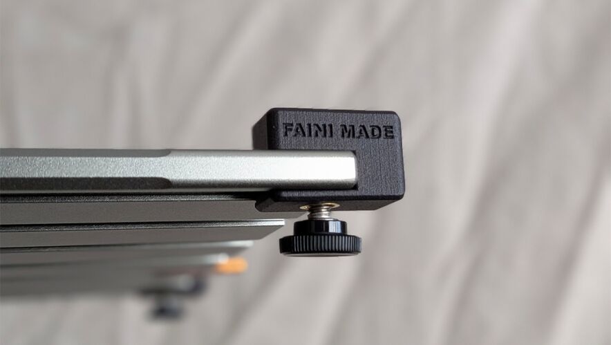 Close-up of a metal camera slider rail with a black end block and a knurled adjustment knob.